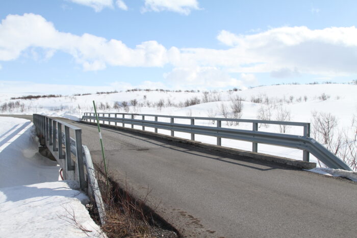 Brücke führt über einen Fluss auf einer schneebedeckten Landschaft