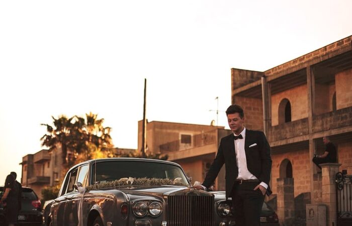 Mann im Anzug vor einem Luxusauto