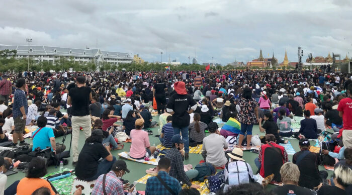 Tausende Menschen sitzen auf einem weiten Platz