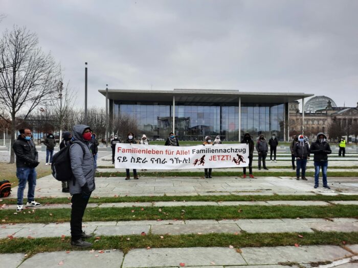 Demonstrationsteilnehmer:innen stehen mit Abstand vor dem Bundeskanzler:innenamt