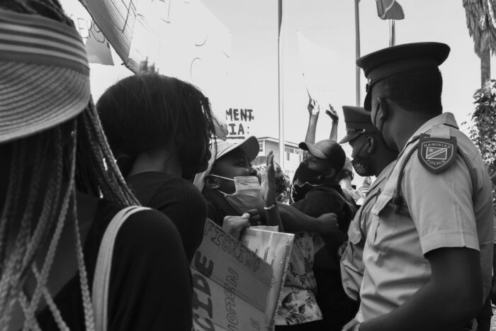 Protestierende skandieren vor zwei Polizisten