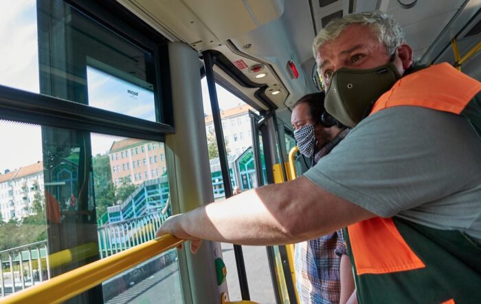 Zwei Personen mit Masken in einem Bus.