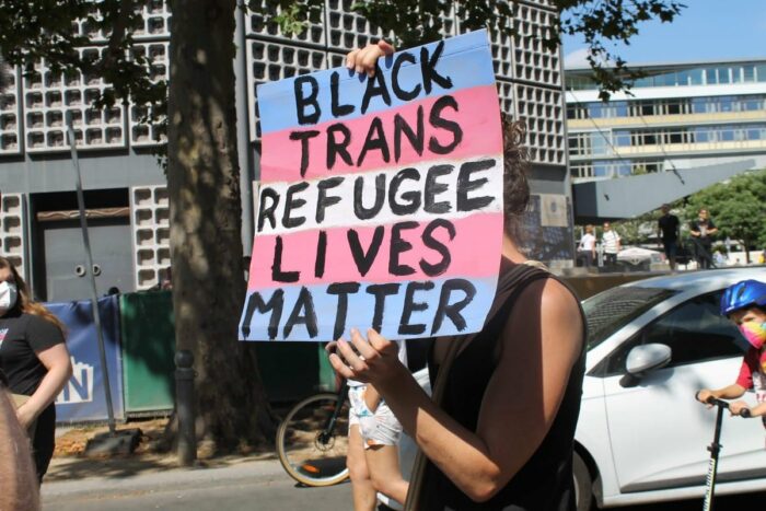 Person hät ein Platak wo drauf steht Black Trans Refugee Lives matter