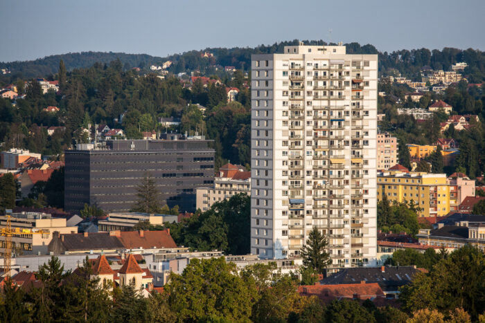 Landschaftsbild Graz mit einem Plattenbau in der MItte und kleineren Wohnhäusern druherum