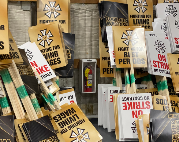 rund um einen Feuerlöscher lehnt eine riesige Menge Schilder(Aufschriften: "On Strike", "Fighting for living wages") an der Wand