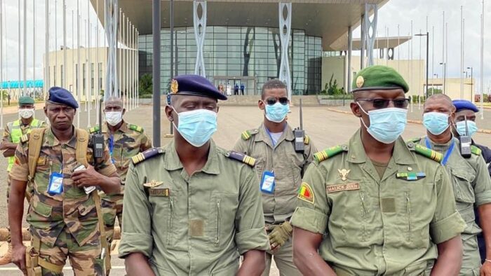 Acht Männer in der Militäruniform der malischen Armee und Maske stellen sich für ein Bild in Formation