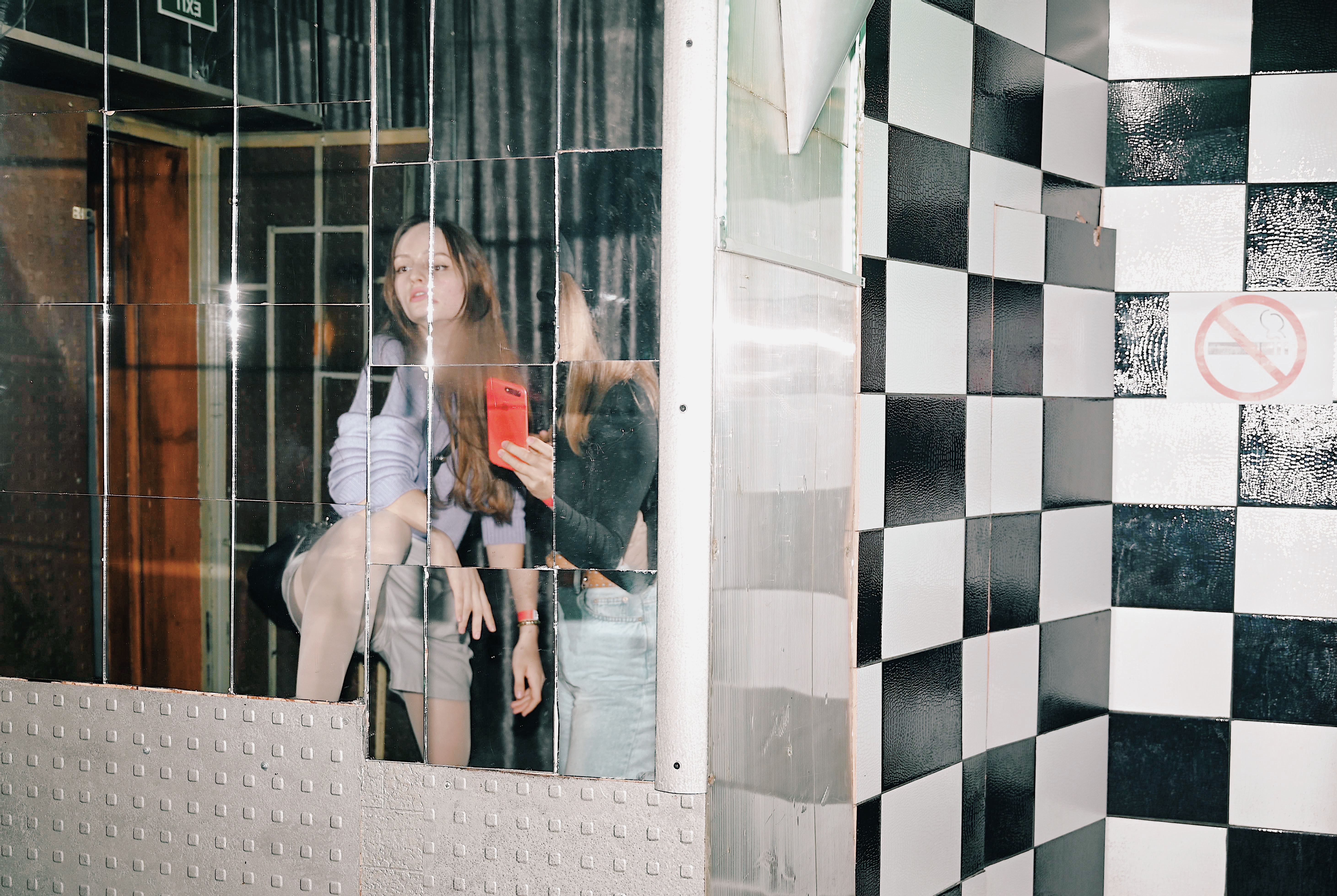 Zwei junge Frauen fotografieren sich vor einem Spiegel