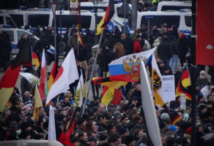 Menschenmenge mit Deutschlandfahnen und einer Russlandfahne, im Hintergrund Polizei