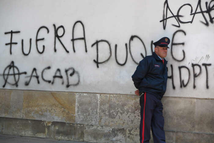 Ein Polizist lehnt an einer Wand in der Altstadt von Bogotá, la Candelaria. Darauf zu lesen ist »Duque raus« sowie das international beliebtes Akronym ACAB.