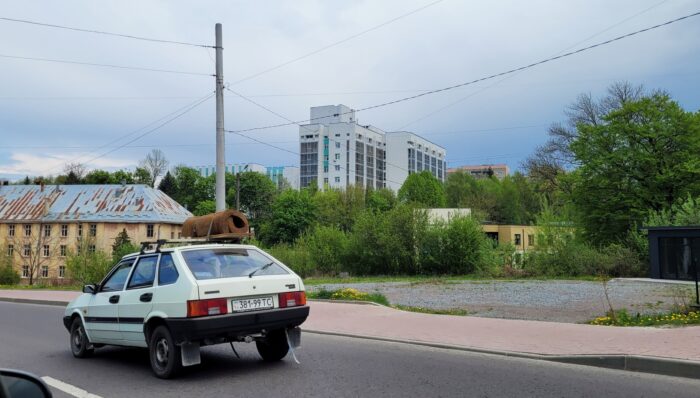 Ein Auto mit einer zusammengerollten Matratze auf dem Dach, bewölkter Himmel