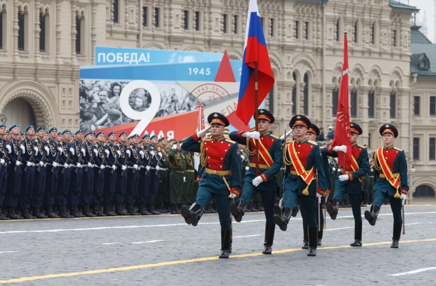Soldaten in Paradeuniformen mit russischer und roter Fahne marschieren vor einer anderen Reihe Soldaten und vor einem Plakat mit der Aufschrift "9 Mai 1945-2019"