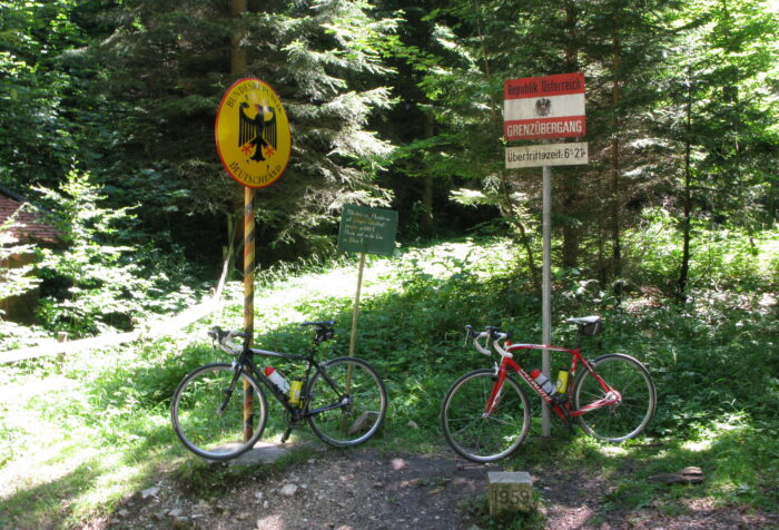In einem stehen zwei Schilder: eines mit dem Bundesadler, eines mit der österreichischen Fahne, an beiden Schildern lehnen Fahrräder