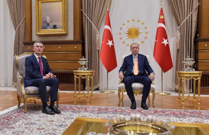 Der türkische Präsident Erdogan sitzt breitbeinig zwischen zwei Türkeifahnen auf einem prunkvollen Sessel in einem prunkvollen Raum, zu seiner Rechten sitzt Nato-Generalsektretär Stoltenberg auf einem weiteren Sessel