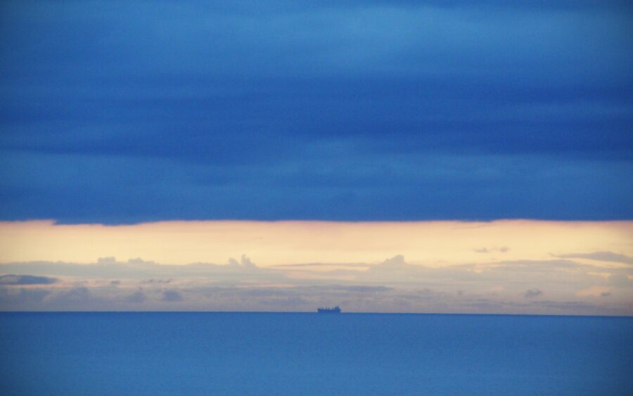 Das Meer mit Blick auf den Horizont; wo sich Himmel und Meer begegnen, ist ein Schiff zu sehen