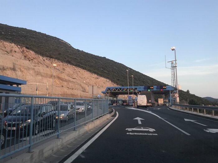 Ein Grenzübergang, an dem Autos warten, dahinter ein Berg