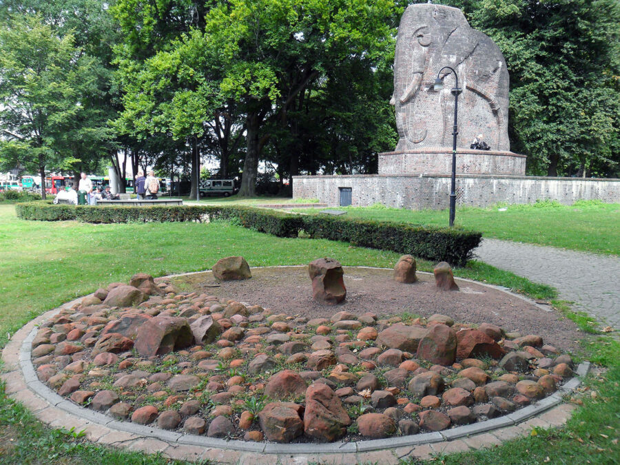 Im Hintergrund eine Skulptur eines Elefanten, im Vordergrund ein Kreis aus Steinen.