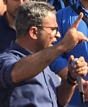 Ein Mann im Profil spricht mit erhobener Hand in ein Mikrofon