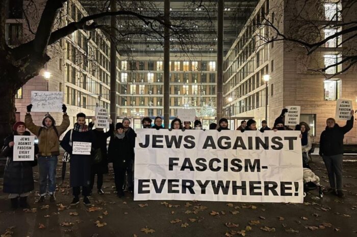 Man sieht etwa 20 Menschen im Dunkeln mit einem Transpi, auf dem Steht "Jews against facism everywhere"