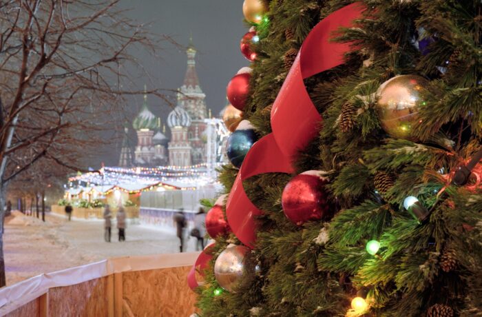 Geschmückter Weihnachtsbaum im Vordergrund, im Hintergrund ist die Basilius Kathedrale am Roten Platz in Moskau zu sehen