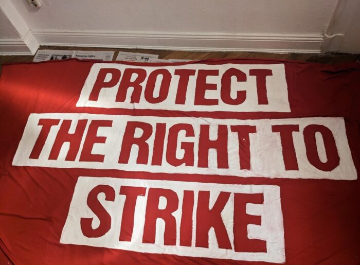 Man sieht ein rotes Transpi, auf dem steht: protect the right to strike.