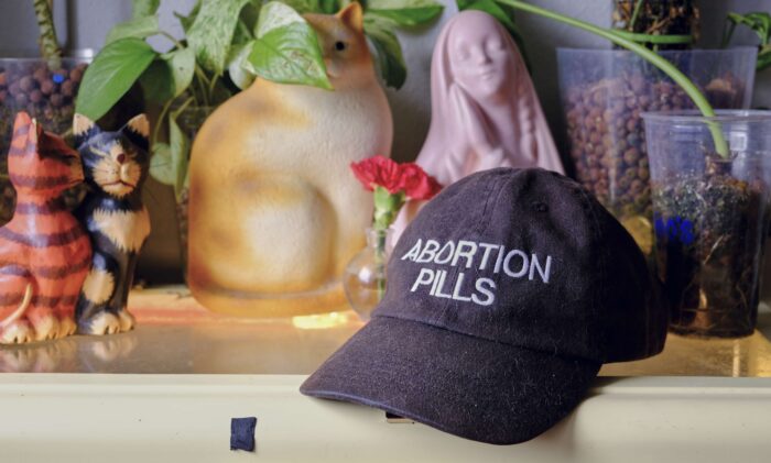 Ein Cap mit der Aufschrift "Abortion Pills" liegt auf einer Kommode.