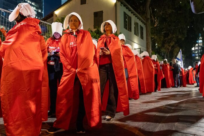 Eine Gruppe von Frauen verkleidet in Kostümen aus der Serie Handmaid's Tale in roten Umhängen und weißen Hauben.