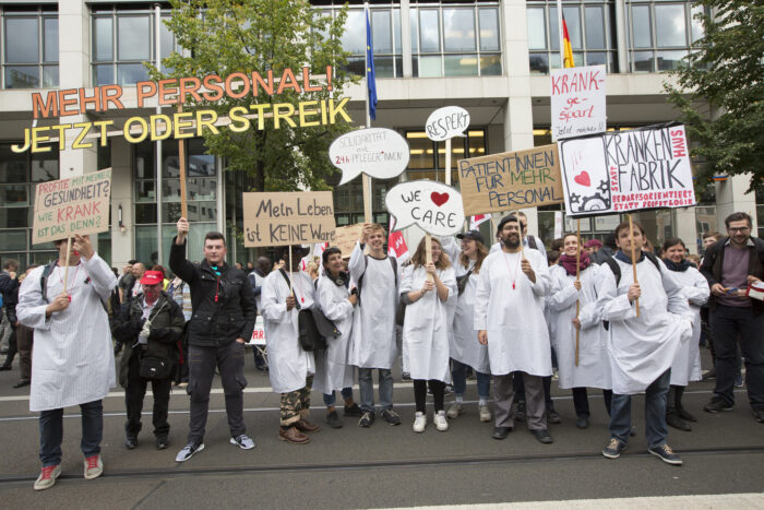 Rund ein Dutzend Demonstrierender, überwiegend in Ärztekitteln, die Protestschilder hochhalten.