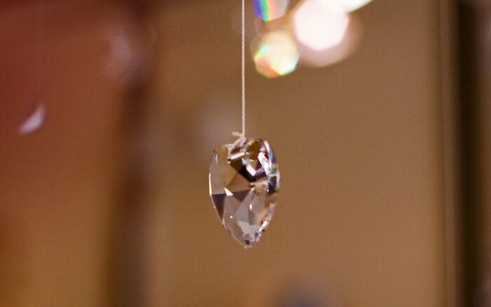 Das Bild zeigt ein glitzerndes Kristallherz, das an einer Schnur hängt und als Pendel benutzt wird.