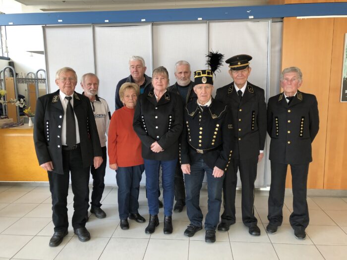 Eine Gruppe von ehemaligen Bergleuten, die meisten in ihren Uniformen, und eine Frau ohne Uniform.