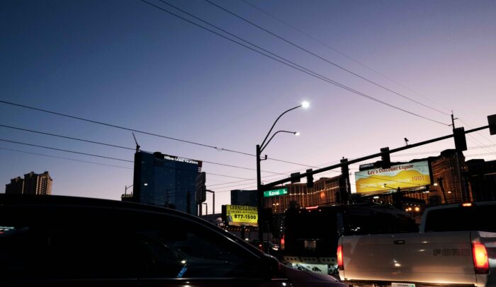 Autos, Hotels, beleuchtete Billboards und Stromleitungen in einer US-Stadt bei Abendlicht