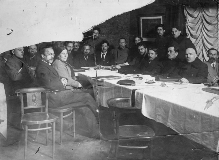 Eine Gruppe von Personen in schicker Kleidung an einem Tisch mit weißer Tischdecke.