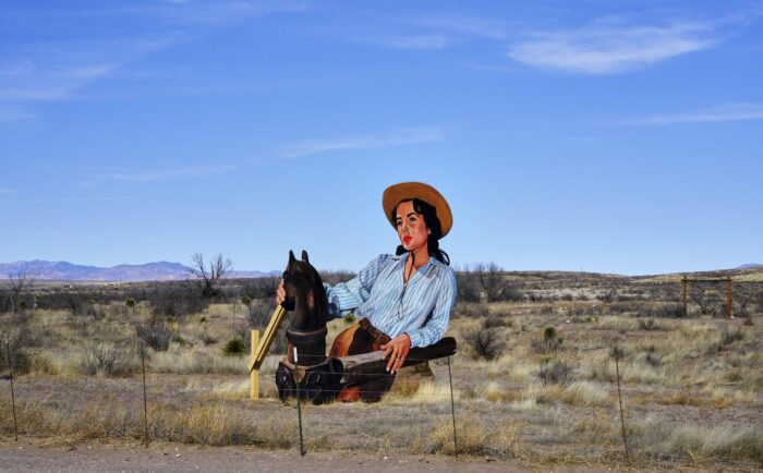 Aufstellfigur einer Frau in Cowboy-Outfit auf einem vertrockneten Feld