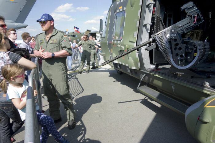 Kinder und Erwachsene sehen sich auf der Internationalen Luft- und Raumfahrtausstellung in Berlin 2018 einen Nato-Helikopter an. Aus der offenen Tür ragt ein Waffenrohr Richtung Publikum. Neben dem Helikopter steht ein Soldat mit Bundeswehabzeichen.