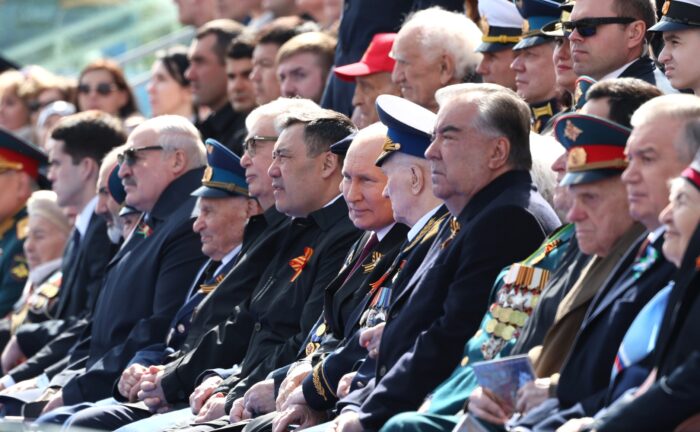 Putin sitzt zwischen Politikern und Militärs in Uniformen und mit vielen Orden