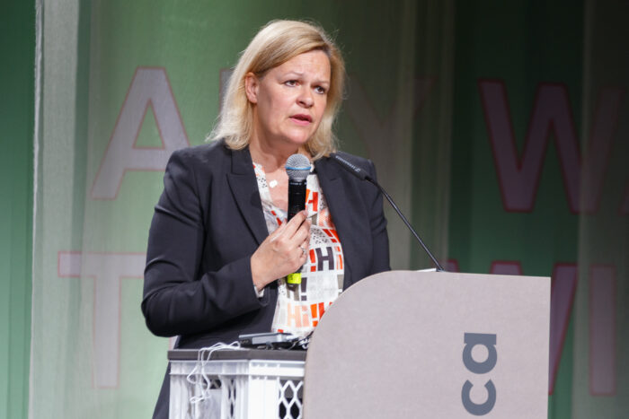 Bundesinnenministerin Nancy Faeser steht an einem Rednerpult und hat ein Mikrofon in der Hand.