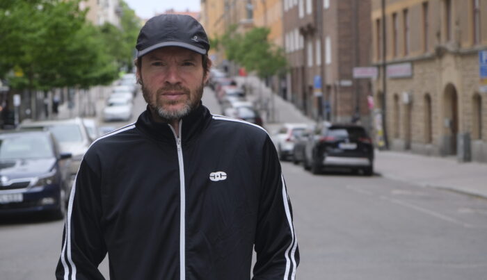 Ein Foto von Gabriel Kuhn. Er trägt eine dunkle Trainingsjacke und eine Cap. Im Hintergrund ist eine Straße