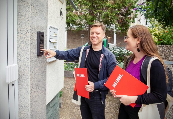 Martin Schirdewan und Janine Wissler, beide mit Linksparteimappen, klingeln an einer Haustür.