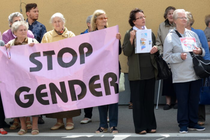 Foto von weißen, alten Frauen mit einem Stop Gender Transpi in der Hand
