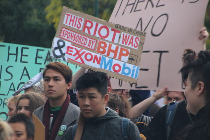 Foto eines Klimastreiks in Melbourne. Auf einem Schild steht "This Riot was sponsoored by BP and ExxonMobile"