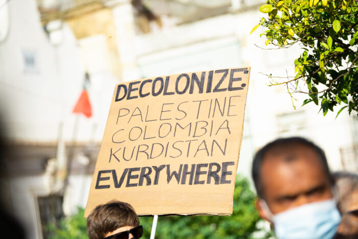 Foto von einem Demoplakat. Darauf steht "Decolonize Palestine, Colombia, Kurdistan, Everywhere"