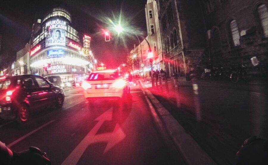 Dunkle Straßenszene, vom vorderen Auto leuchten grelle Bremslichter, im Hintergrund sind die Neukölln-Arkaden czu sehen