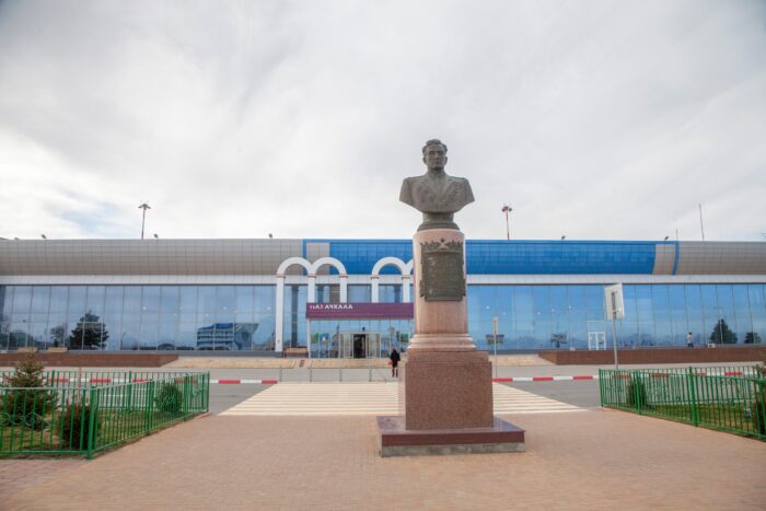 Im Vordergrund eine Statue, dahinter ein Eingang zu einem Flughafengebäude.