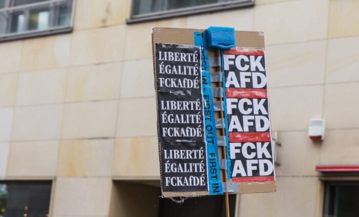 Ein Schild vor einer Mauer, auf der linken Seite steht "Liberté, Egalité, FCKAfDé", auf der rechten Seite mehrmals in fetten Buchstaben FCKAFD