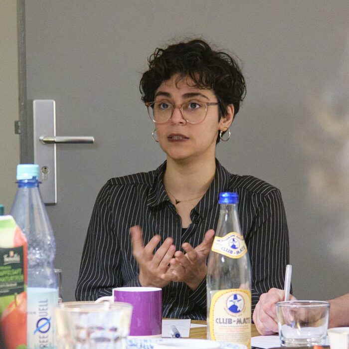 Sanaz Azimipour sitzt an einem Tisch und spricht
