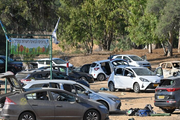 Ein sandiger Parkplatz, darauf kreuz und quer stehende Autos, die zum Teil beschädigt sind.