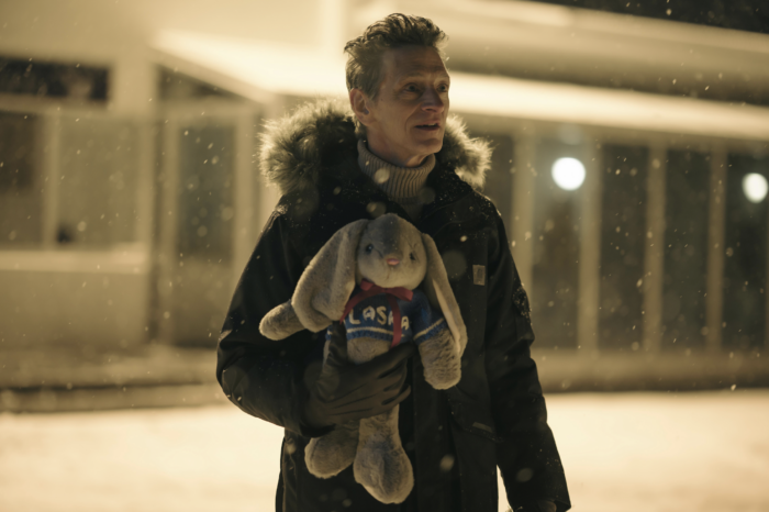 Hank Prior, eine Figur aus der Serie True Detective, steht im Schnee vor einem Gebäude und wartet auf jemanden, in der Hand hält er einen Stoffhasen.