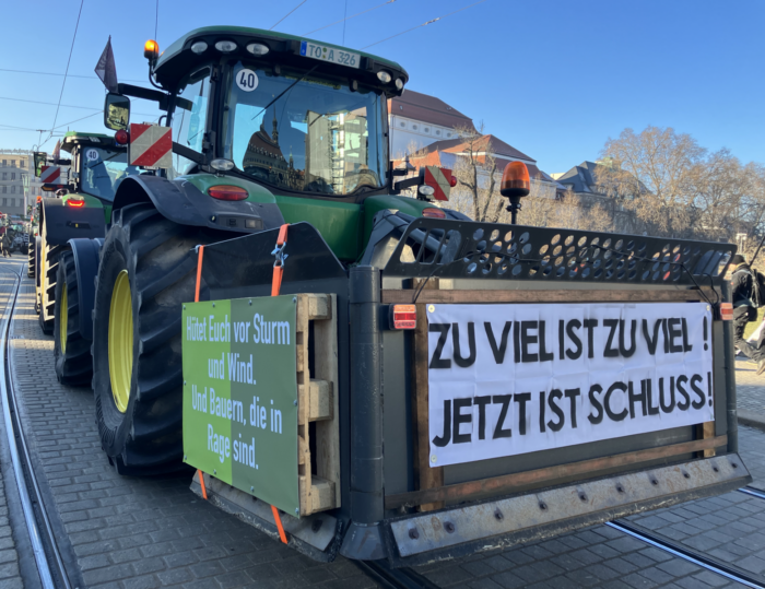 Ein Traktor mit einem Demobanner. Aufschrift: Zu viel ist zu viel. Jetzt ist Schluss!