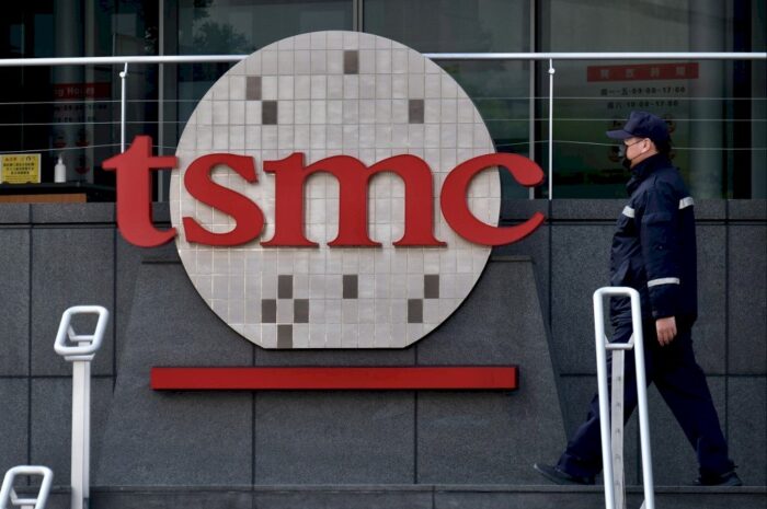 Logo von TSMC an einem Gebäude, ein Wachmann, der vorbeigeht.