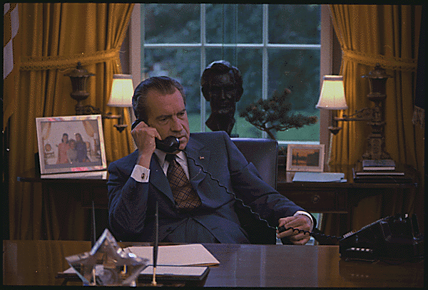 Das Bild zeigt den ehemaligen US-Präsidenten Richard Nixon, an einem Schreibtisch sitzend und mit einem Telefonhörer in der Hand