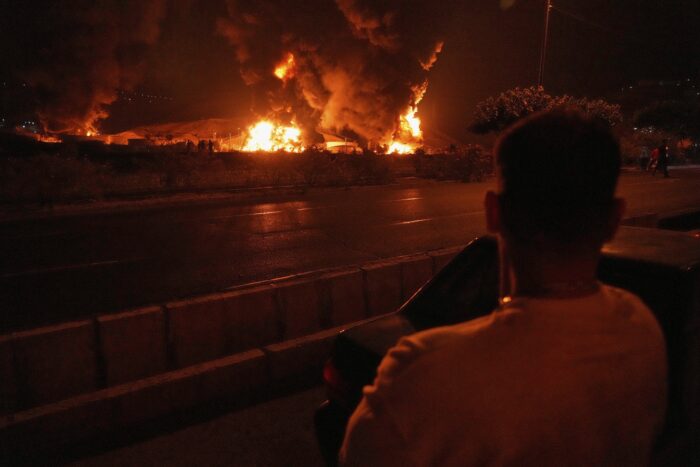 Foto von einem Mann der auf ein riesiges Feuer nach einem Bombeneinschlag blickt